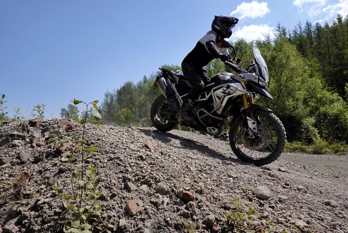 Woman riding Triumph Tiger 900 Rally Pro on a gravel hill at the Triumph Adventure Academy in Wales