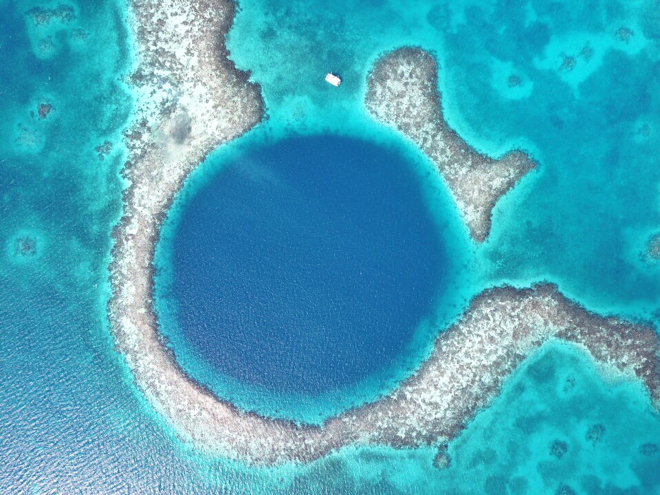 The Blue Hole in Belize showing a catamaran just outside the reefs surrounding the deep blue hole
