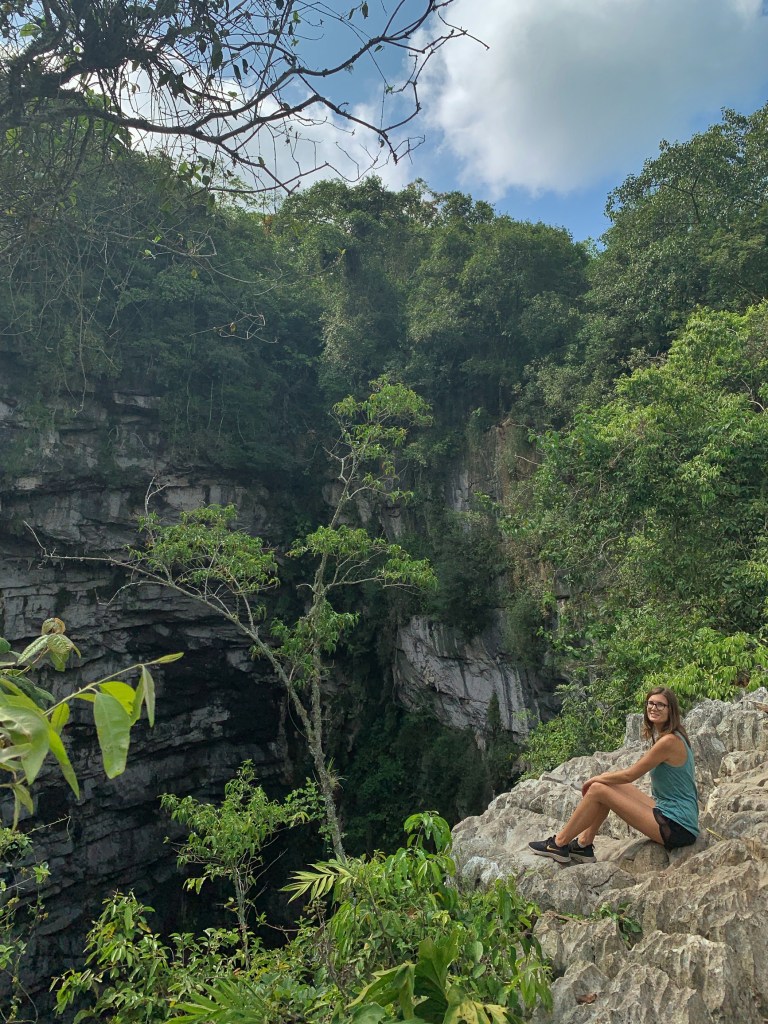 Woman sitting at the ledge of the cave of swallows in Huasteca Potosina, known as Sotano de las Golondrinas